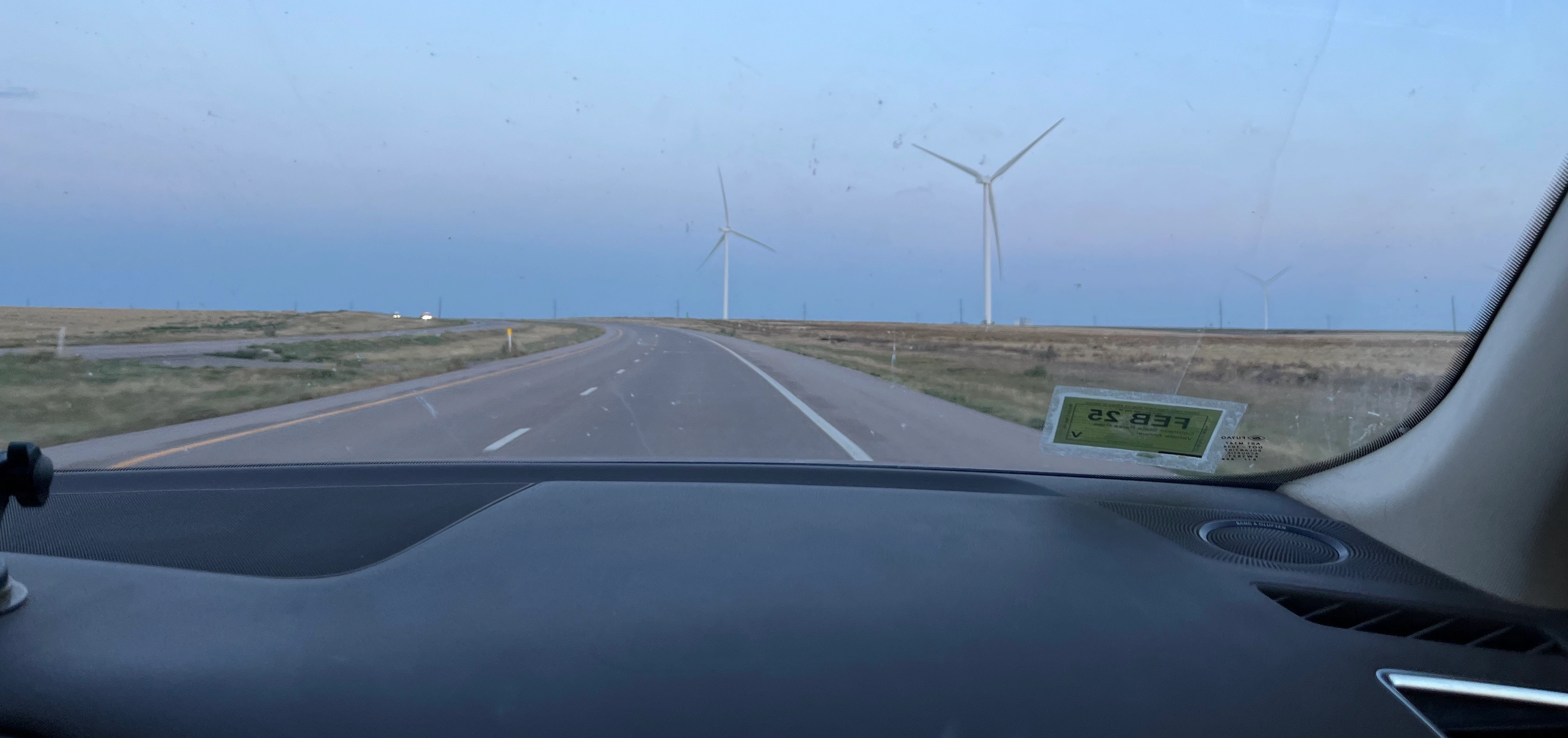 A standard view out the front windshield of the car. Just plains and windmills.